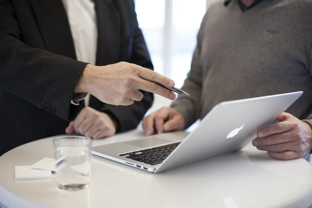 Small group of anonymous people discussing around a table with laptop and brochures