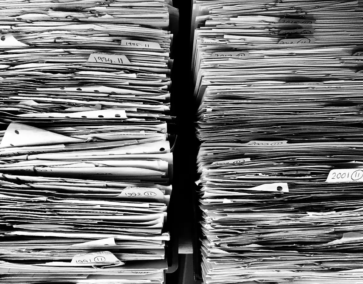 A well-lit desk strewn with printed course catalogs and a pen beside an open booklet titled 'Parcours professionnel', hands taking notes in the background, no logos